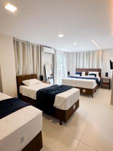 a bedroom with two beds and a room with two chairs at Home Studio in Sobral
