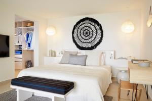 a bedroom with a white bed with a black bench on it at Eagles Villas - Small Luxury Hotels of The World in Ouranoupoli