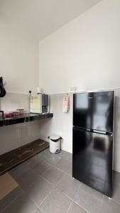 a kitchen with a black refrigerator in a room at Homestay Azizi in Seri Iskandar