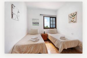 two beds in a white room with a window at Villa Luisa Atico in Tigaday