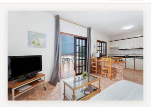 a living room with a flat screen tv and a kitchen at Villa Luisa Atico in Tigaday