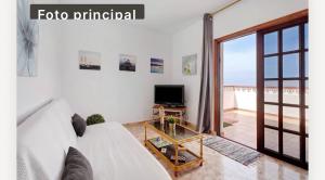 a living room with a white couch and a television at Villa Luisa Atico in Tigaday +3 photos
