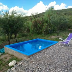 a blue swimming pool in a gravel yard with a chair at Entre Tanto in Luyaba