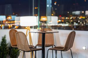 a table with three chairs and a table with a lamp at Occidental Las Palmas in Las Palmas de Gran Canaria