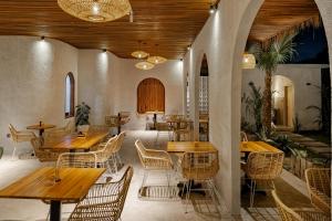 a restaurant with wooden tables and rattan chairs at Dania Cinta Ubud in Ubud
