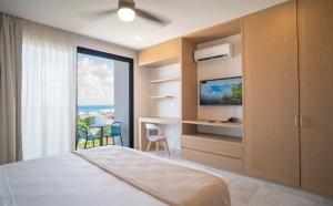 a bedroom with a bed and a tv and a window at abba Suites Playa del Carmen in Playa del Carmen