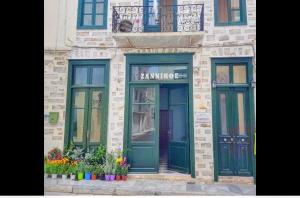 a building with two doors and flowers in front at Zannikos Rooms in Ermoupoli