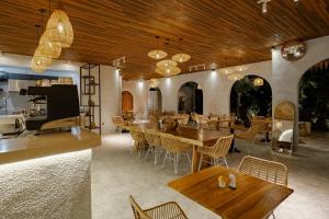 a restaurant with wooden ceilings and tables and chairs at Dania Cinta Ubud in Ubud