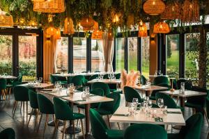 a restaurant with tables and chairs and chandeliers at Hotel Les Suites - Domaine de Crécy in Crécy-la-Chapelle