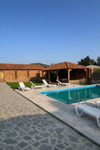 a swimming pool with lounge chairs and a building at Ortevani Guest House in Kvareli
