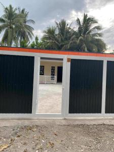a garage with a gate with palm trees in the background at Hayat Apartment Digos City in Dawis