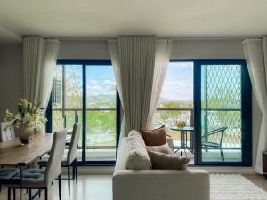 a living room with a couch and a table with chairs at Comfortable 2Bdr Bangtao Space Condo in Ban Thalat Choeng Thale