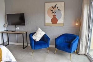 a room with two blue chairs and a table and a television at 1009 Studio Apartment Pont de Val in Parys