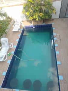 a swimming pool with two chairs and a hose in the water at hospedagem com passeio de quadriciclo in Guapimirim