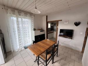 a dining room with a wooden table and a kitchen at Maison Ustou46 in Cahors