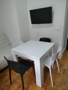 a white table with chairs and a tv on a wall at "Le Betulle 10" cinque minuti dal mare, Self check in in Bibione