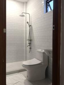 a white bathroom with a toilet and a shower at Casa Sereno Spring Resort in Irosin +7 photos