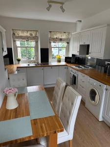 a kitchen with white cabinets and a wooden table at West Cottage, Free Breakfast supplied with free range eggs With log burner in Towton