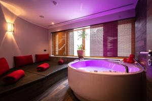 a large bathroom with a large tub with red pillows at Hotel Amselgrundschlößchen in Kurort Rathen