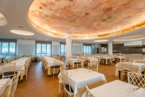 a banquet hall with white tables and a large ceiling at Hotel Canada Palace in Calafell