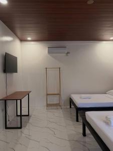 a room with two beds and a table and a tv at Casa Sereno Spring Resort in Irosin