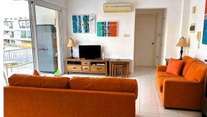 a living room with an orange couch and a television at Peyia Spring in Peyia