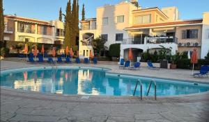 a swimming pool in a courtyard with chairs and buildings at Peyia Spring in Peyia +5 photos