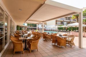 an outdoor restaurant with tables and chairs and a pool at Hotel Canada Palace in Calafell