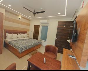 a bedroom with a bed and a television and a desk at Hotel Kanha palace in Lucknow
