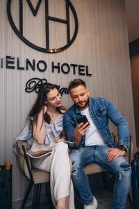 a man and woman sitting in a chair looking at a cell phone at Mielno Hotel Boutique in Mielno