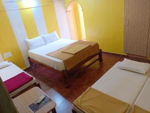 a small room with two beds and two tables at Mabla House in Gokarna