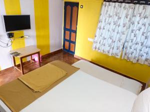 a bedroom with a bed and a tv and a window at Mabla House in Gokarna