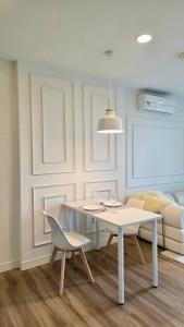 a white dining room with a table and a chair at i-CONDO B2072 in Ban Liap