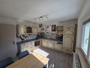 a kitchen with white cabinets and a wooden table and a dining room at Ferienwohnung Waldbach in Arrach