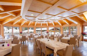 a dining room with white tables and chairs at Hotel Crepei in Pozza di Fassa