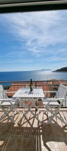 a person sitting on a white picnic table with two chairs at Matea Apartments Milna in Milna
