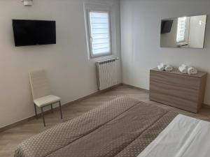a bedroom with a bed and a chair and a tv at House 149 in Ferrara
