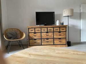 a television on top of a dresser with a chair at La Mouette de Ripaille in Thonon-les-Bains