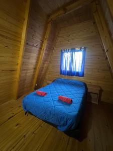 a bed in a wooden room with two red pillows on it at Ventana al Champaqui in Yacanto
