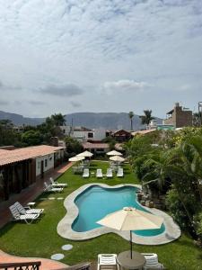 a swimming pool with an umbrella and lounge chairs at Oro Viejo in Nazca