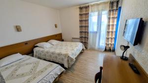 a hotel room with two beds and a table and a television at Le Provence in Manosque