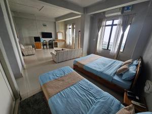 a bedroom with two beds and a living room at Seasons Hotel in Lunglei