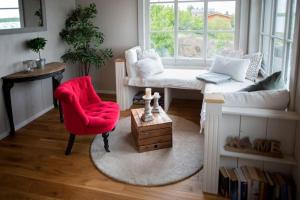 a living room with a red chair and a window at Kleine SeenSucht in Neukieritzsch +3 photos