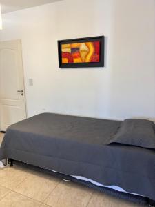 a bed in a bedroom with a picture on the wall at Amelia 2-1 in Villa Carlos Paz