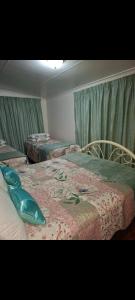 three beds in a room with green drapes at Eagles guest house Piet Retief in Piet Retief