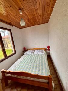 a bed in a room with a wooden ceiling at Le Tuc de Rose in Mimizan