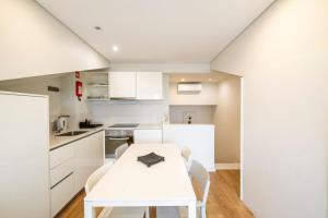 a white kitchen with a white table and chairs at Terro Collection - Alcaide in Braga
