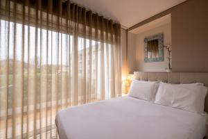 a bedroom with a white bed and a large window at Terro Collection - Alcaide in Braga