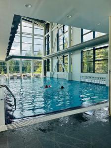 a large swimming pool with two people swimming in it at White & Wood Suite C302, at Euphoria SPA Borovets in Borovets