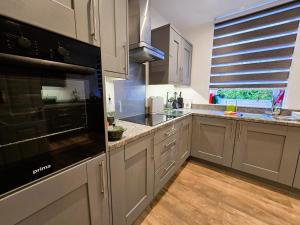 a kitchen with white cabinets and a black appliance at The Harbour House - Deluxe Town Centre Property in Rothesay